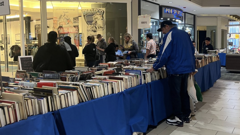 A man looks through rows of books on a table in the middle of Livonia's Laurel Park Place mall during Bookstock.
