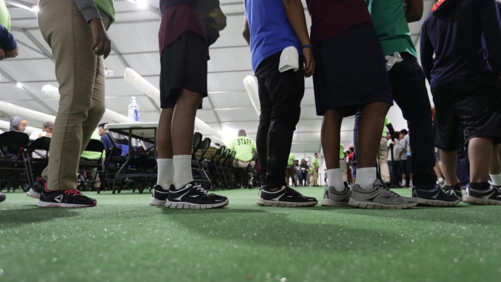 FILE - Immigrants line up in the dining hall at a U.S. government holding center for migrant children, July 9, 2019, in Carrizo Springs, Texas.