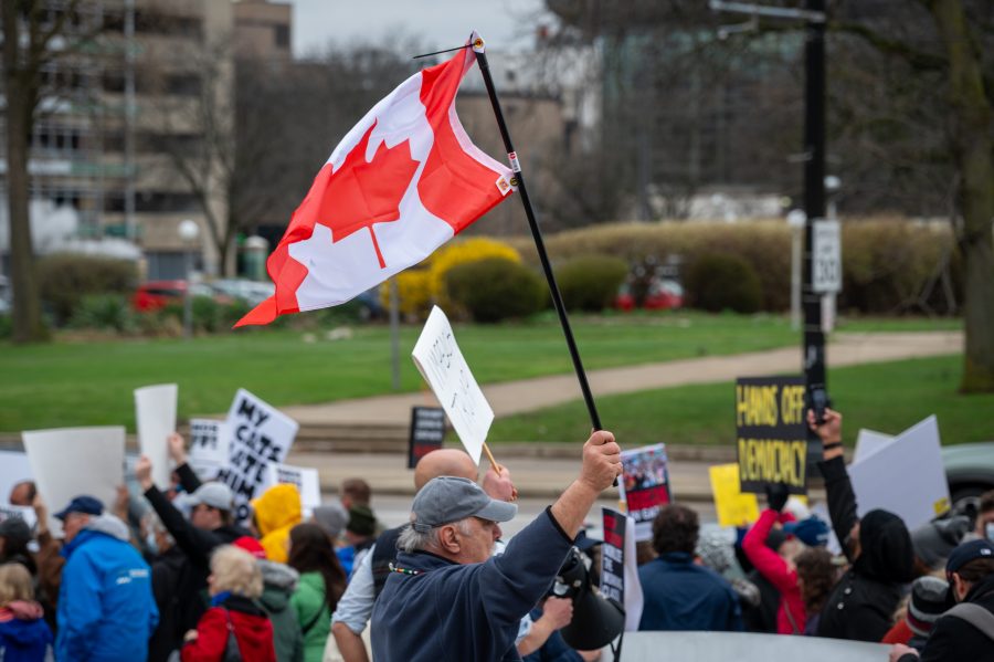 Jim Sanders of White Lake Twp. waves a Canadian Flag during the #HandsOff protest on April 5, 2025.