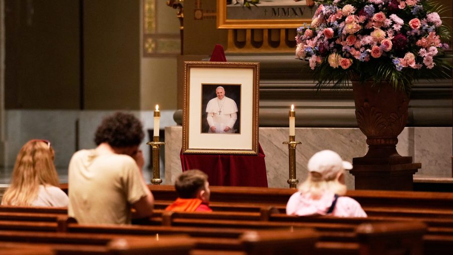 People pray near a picture of Pope Francis inside the Cathedral Basilica of Saints Peter and Paul, Monday, April 21, 2025, in Philadelphia.