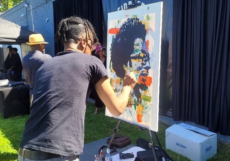 Artist J.R. Strozier paints a portrait of Amp Fiddler during the Amp Fiddler Avenue unveiling on Friday, May 16, 2025.