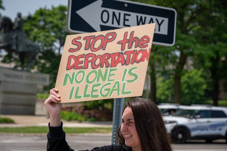 A demonstrator holds up a handmade sign that says "Stop the deportation No one is illegal"