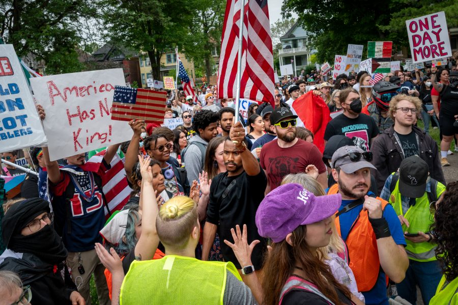A man waves an American flag in a crowd of protesters holding homemade signs