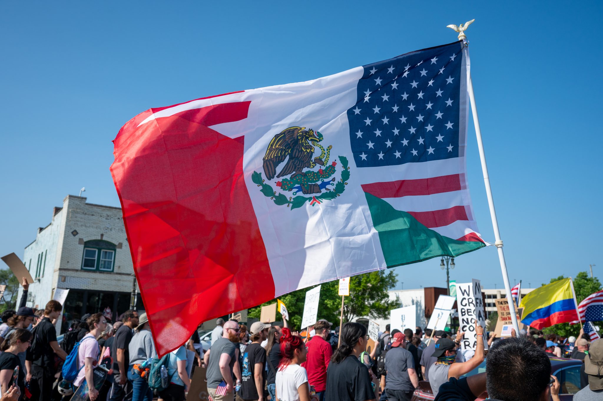 A half-American, half-Mexican flag is waved in a crowd of protesters