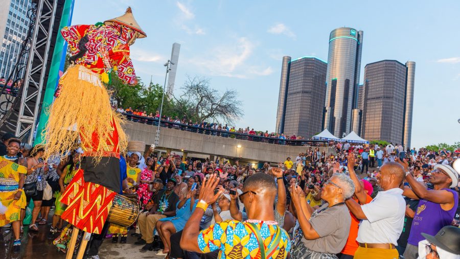 A crowd in Hart Plaza watches a performer on stilts at the African World Festival