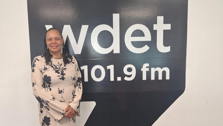 DaNetta Simpson poses in front of the WDET logo