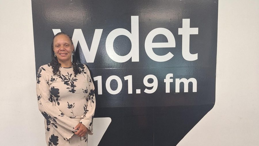 DaNetta Simpson poses in front of the WDET logo