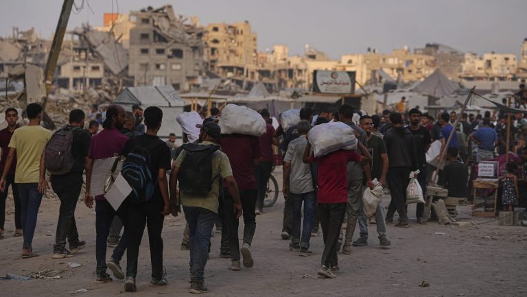 Palestinians carry sacks of food and humanitarian aid unloaded from trucks convoy that had been heading to Gaza City, in the northern Gaza Strip, Sunday, June 22, 2025.