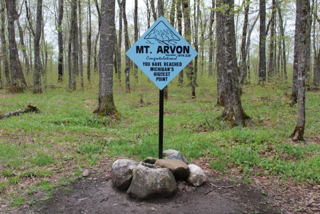 A sign in the woods denotes Michigan's highest point.