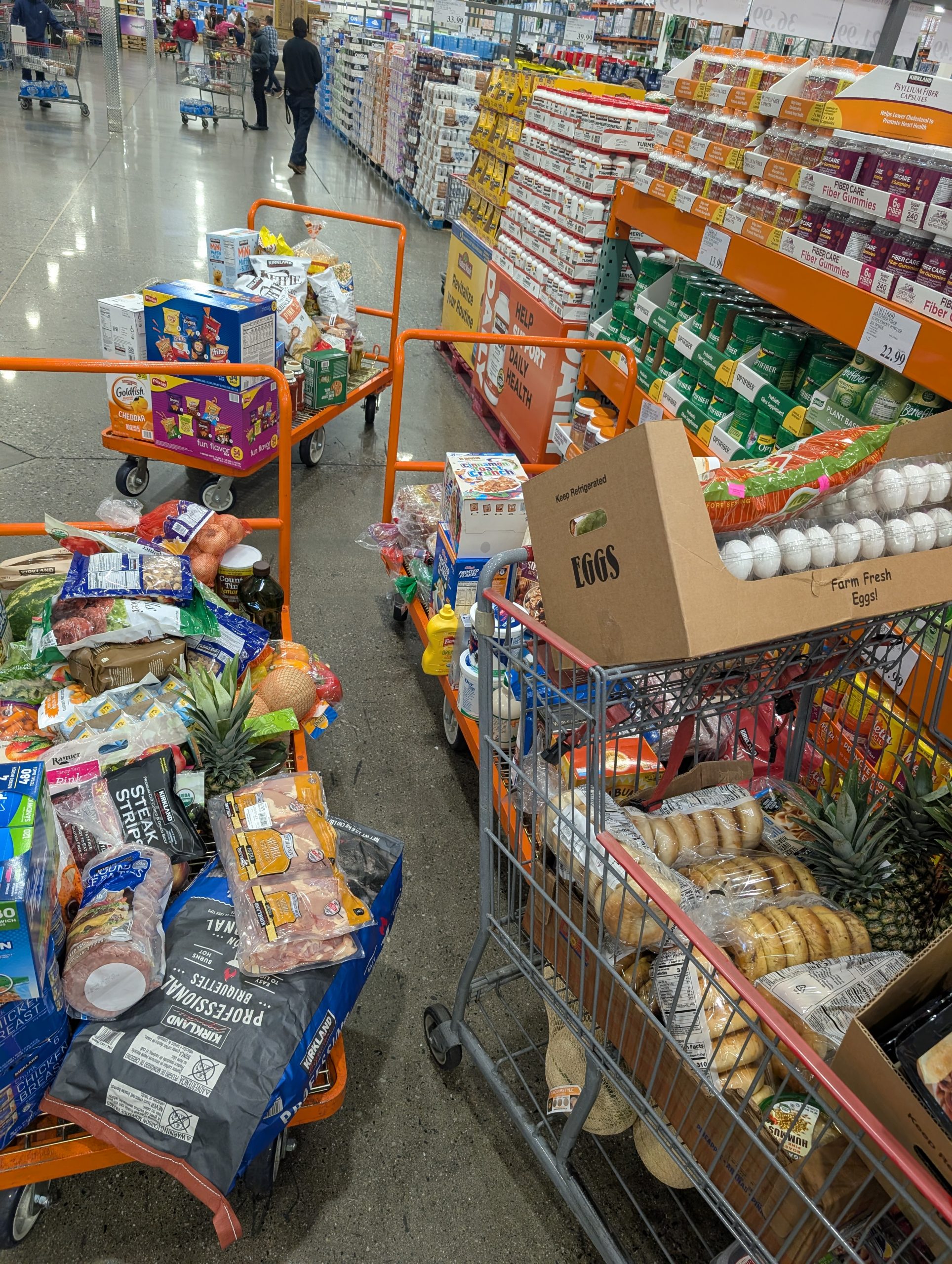 Three carts overflowing with groceries at a big box store