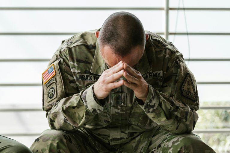 A solder sitting with his hands holding his head