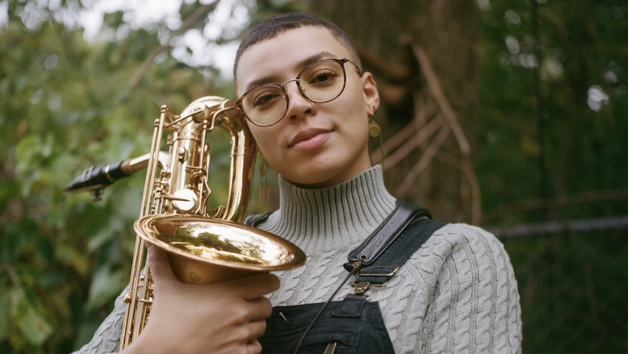 Kaleigh Wilder is outside holding her saxophone near her face.
