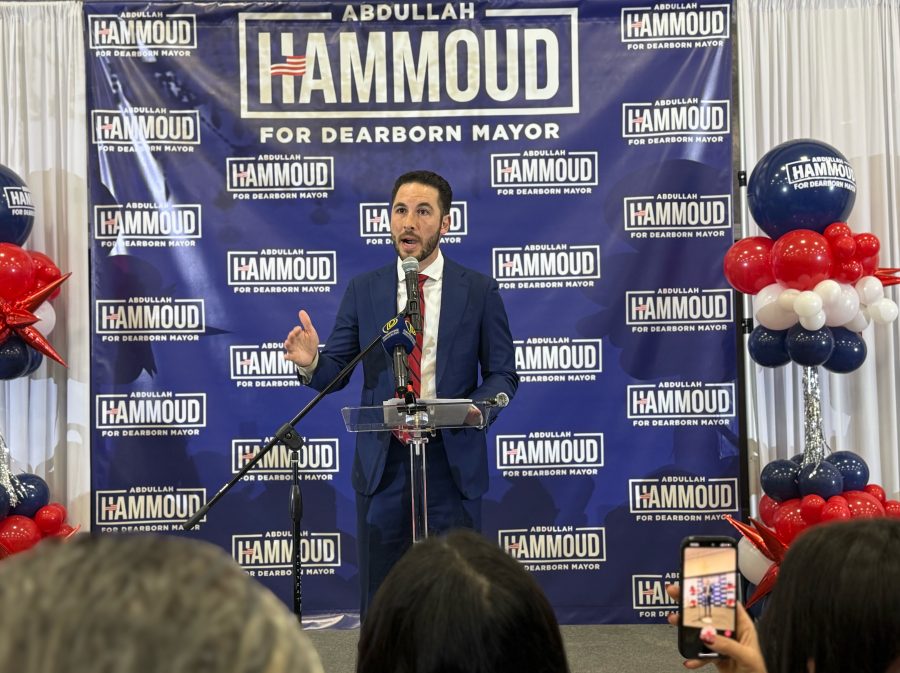 Hammoud stands in front of a backdrop of his campaign logo, speaking to the crowd gathered to watch the votes for Dearborn mayor come in.