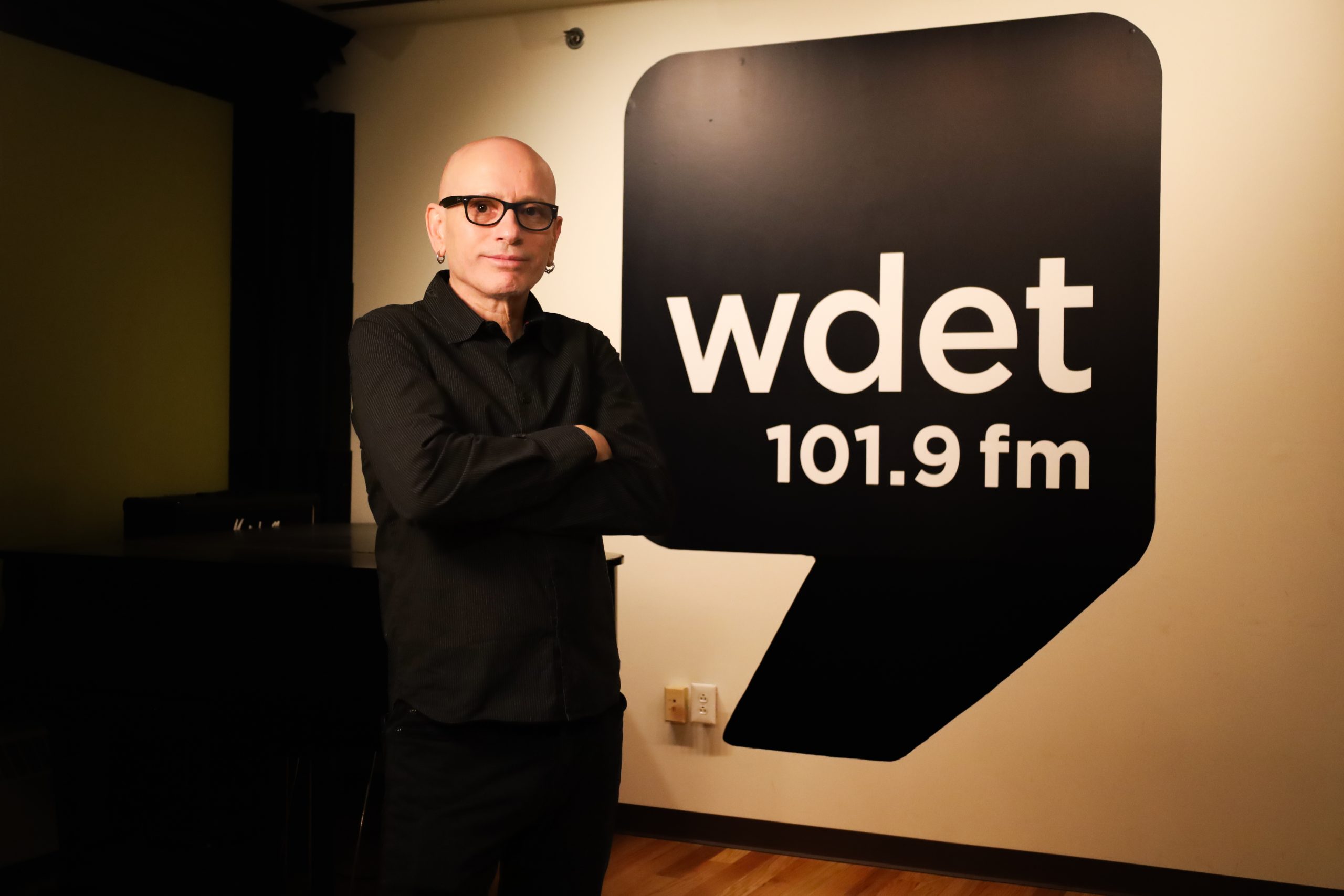 Darren Revell stands in front of a large WDET logo decal.