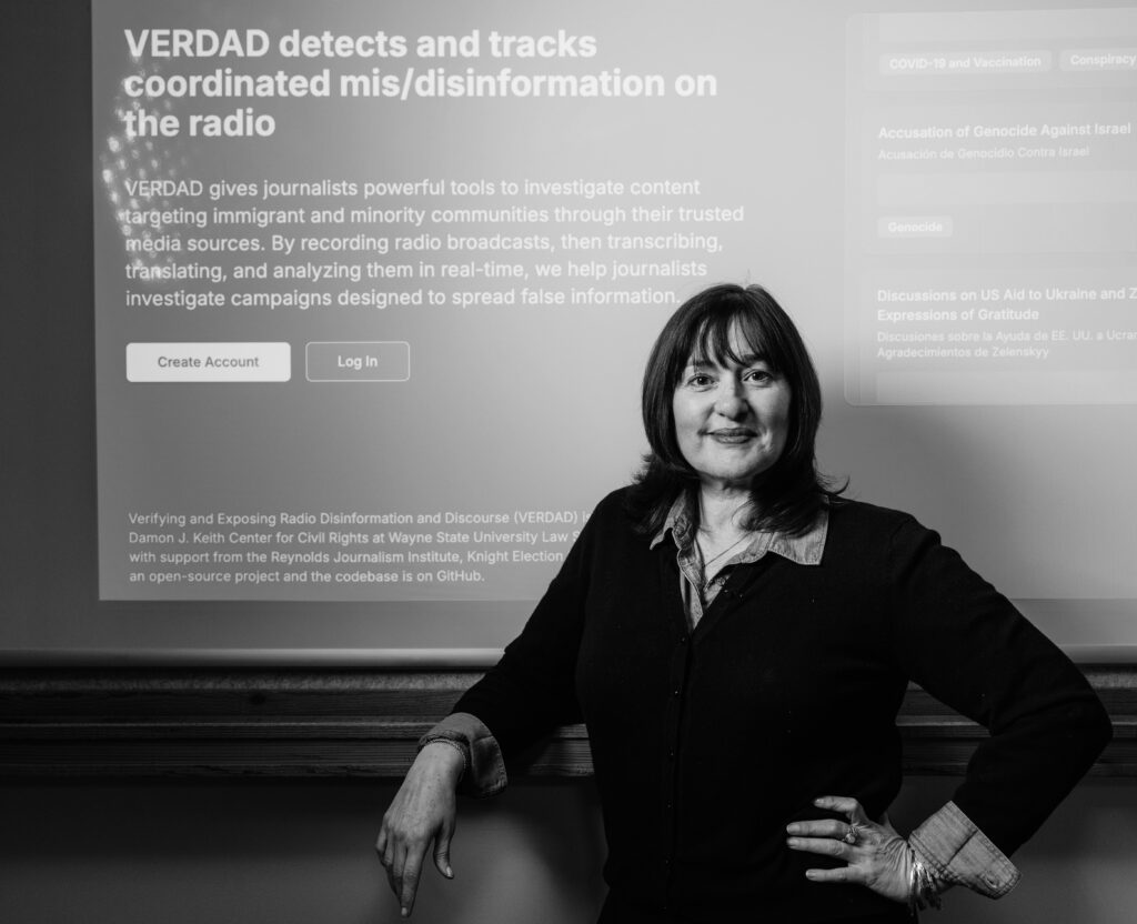 Journalist Martina Guzman stands in front of a presentation describing her ai tool VERDAD that helps detect disinformation happening on Latino radio stations.