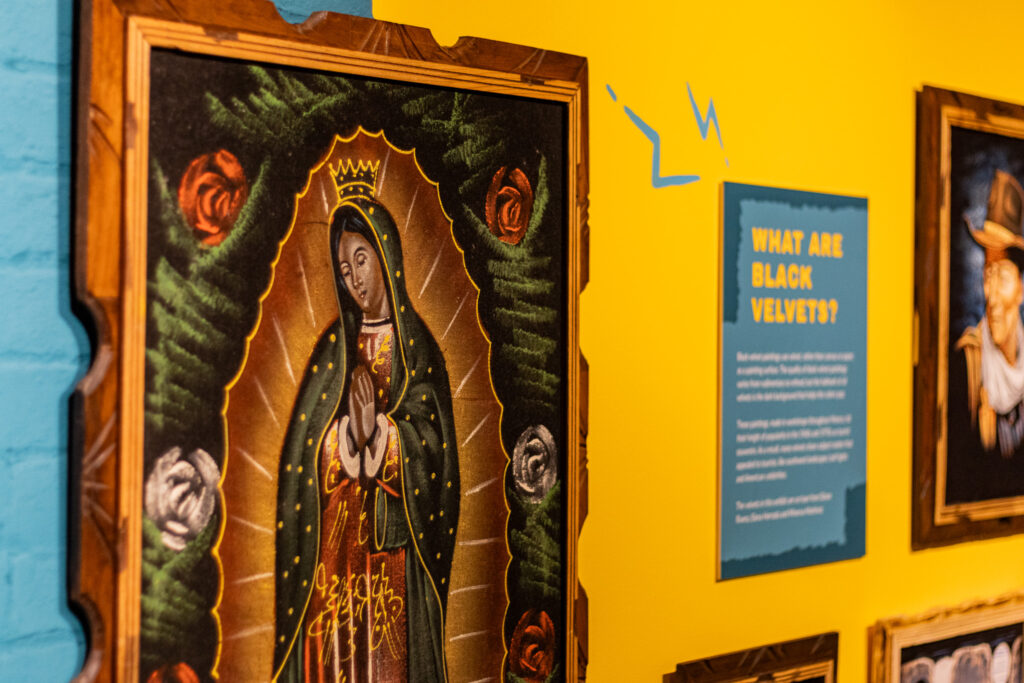 Lady Guadalupe wearing a crown, surrounded by a golden aura and roses on black velvet.