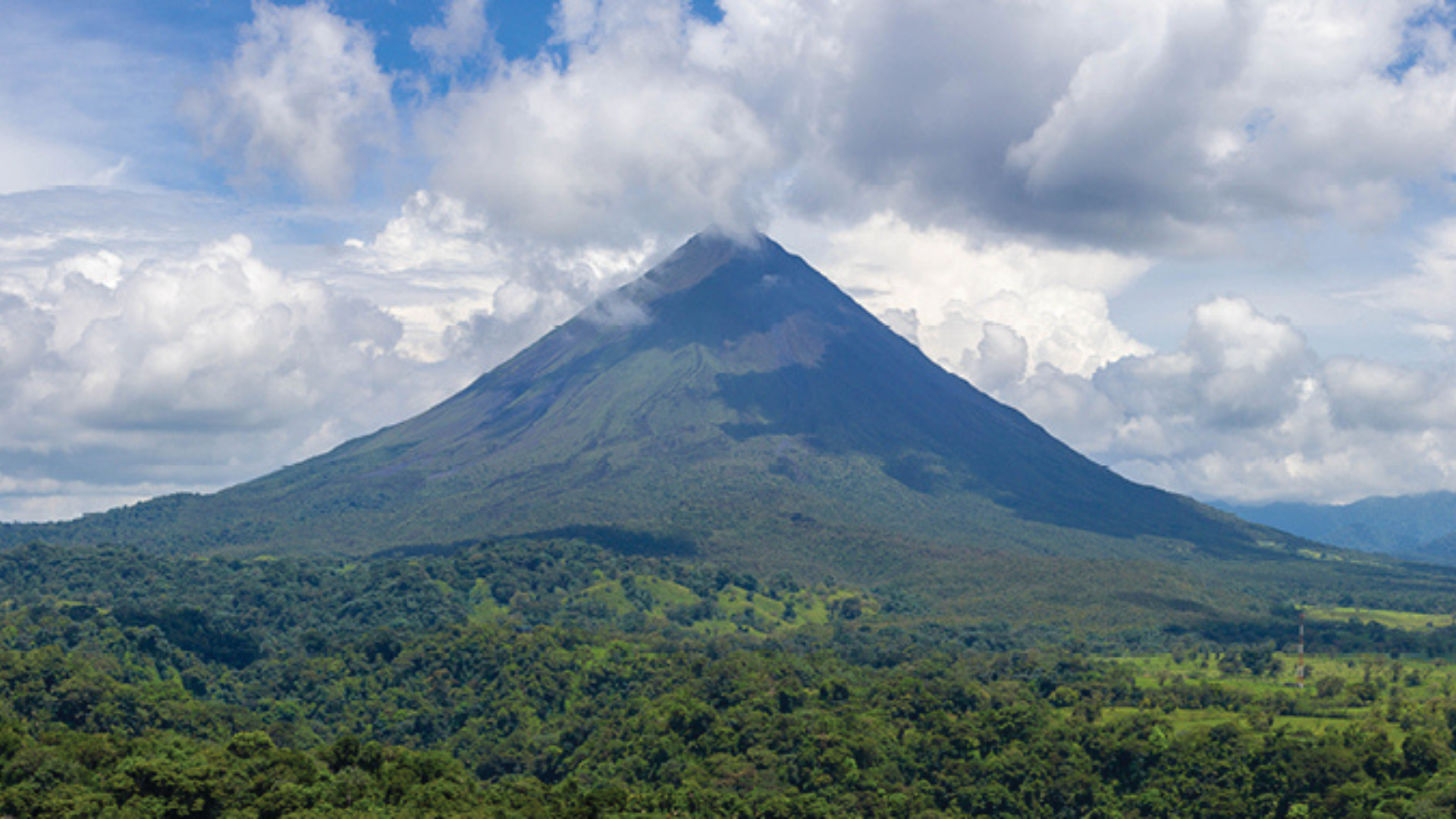 A volcano rises up from a lush green jungle
