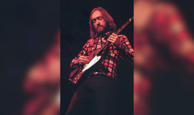 Dave Mason in a red flannel playing guitar.