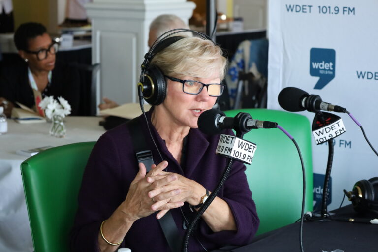 Jennifer Granholm is behind a WDET microphone talking to a reporter off screen