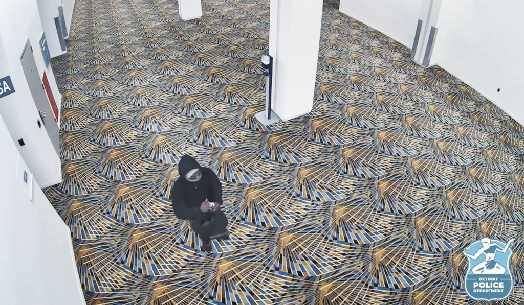 A man in a black hoodie holds a water bottle full of gasoline.