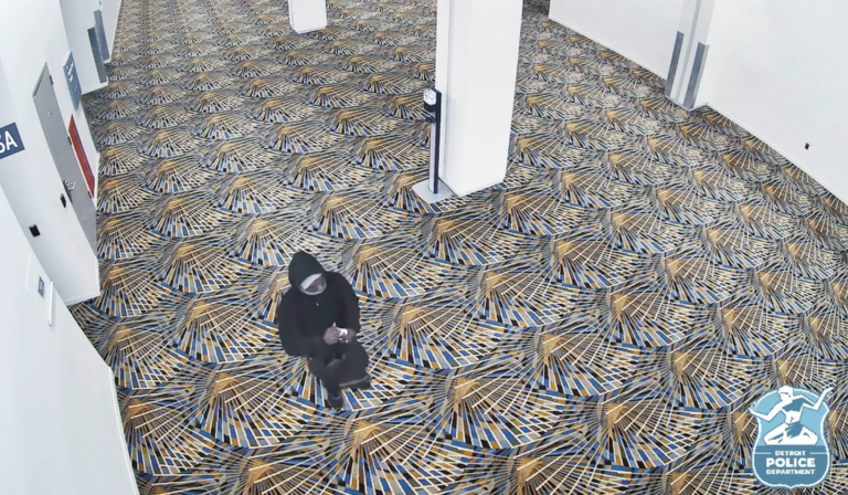 A man in a black hoodie holds a water bottle full of gasoline.