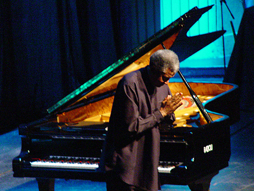 Ibrahim bows in front of an open piano.