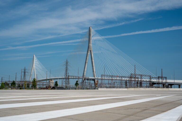 Striped pavement in front of the towering Gordie Howe Bridge.