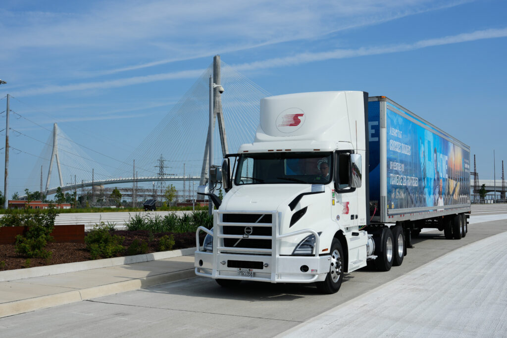 A semi truck is parked in front of the Gordie Howe bridge.