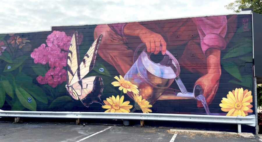 A mural depicting someone watering yellow flowers with a watering can. A yellow swallowtail butterfly rests on a pink flower.