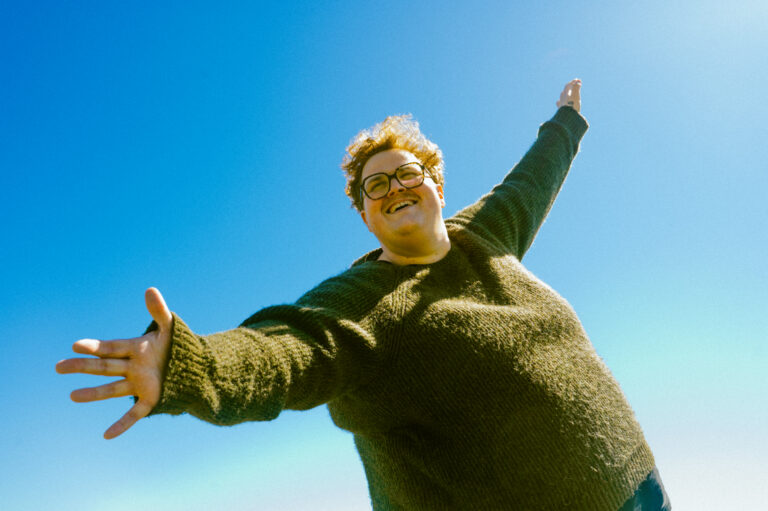 Michigander leader singer Jason Singer in front of a blue sky.